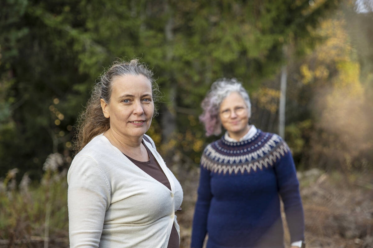 Två trevliga kvinnor på promenad i skogen.