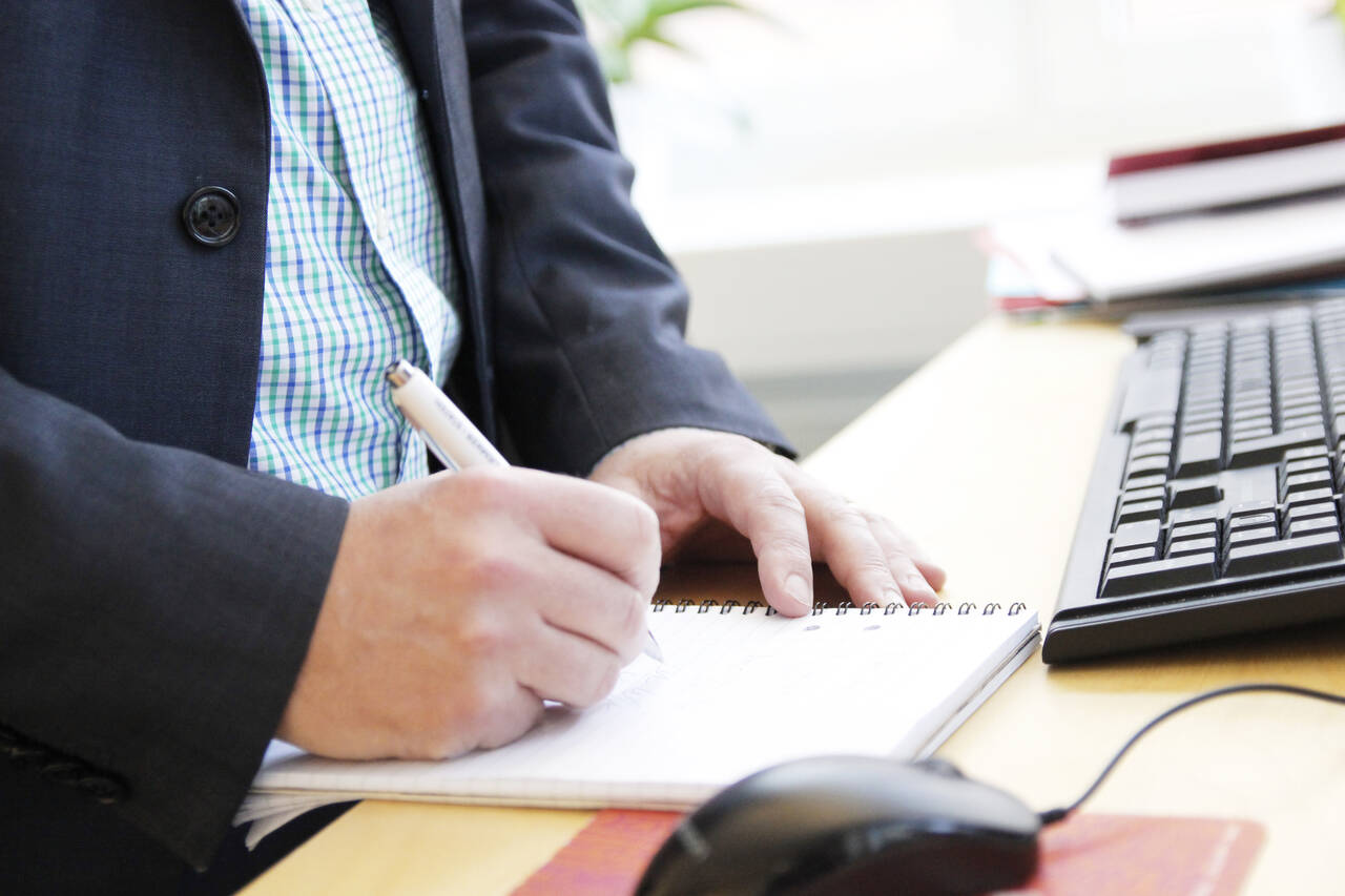 två händer som skriver anteckningar på ett block