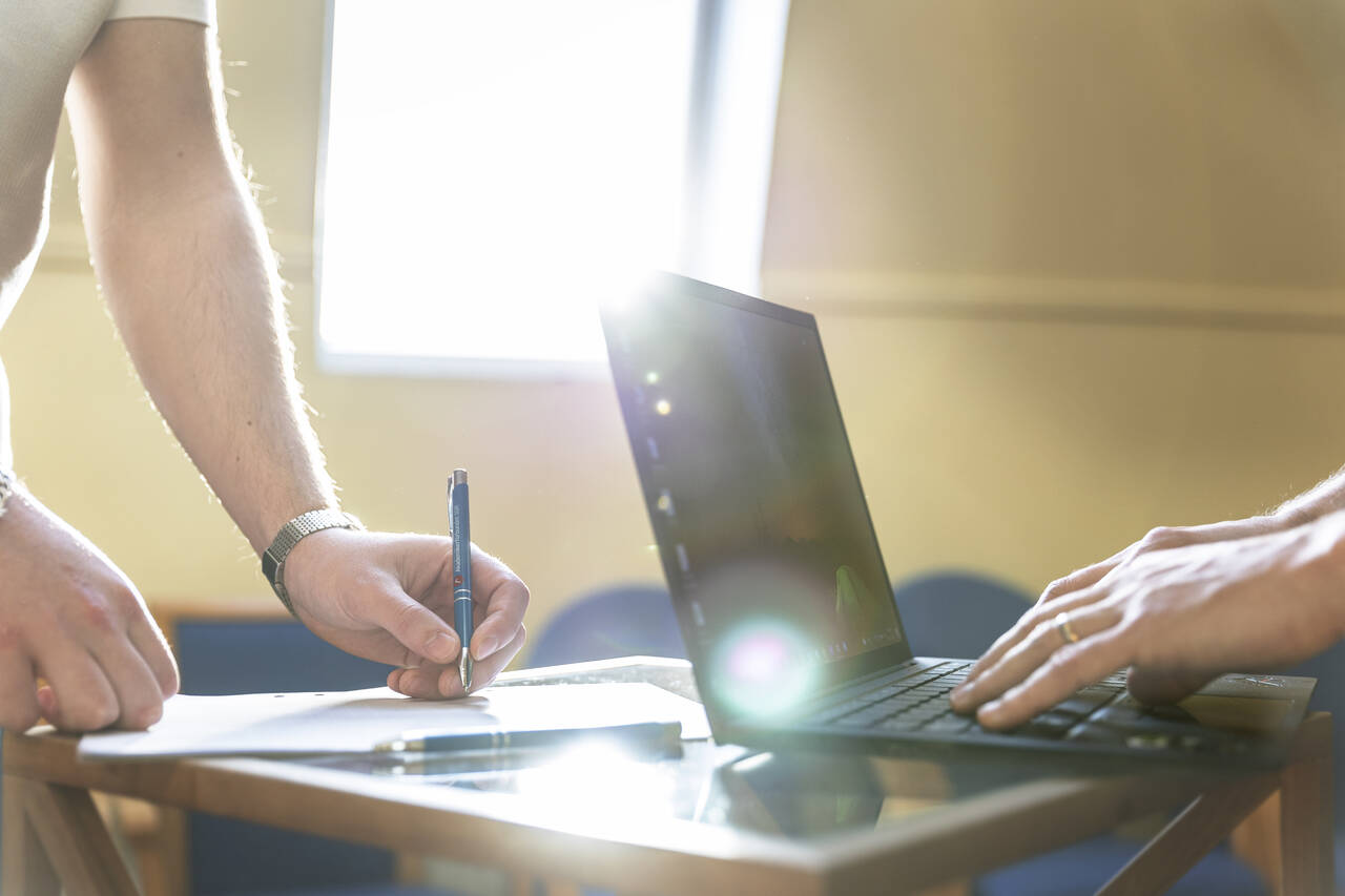 händer som skriver på dator och för hand
