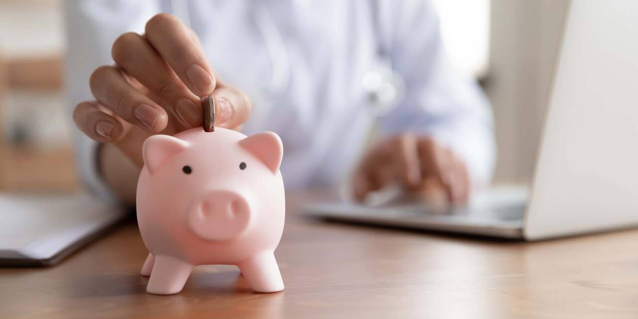 En hand lägger en peng i en spargris.